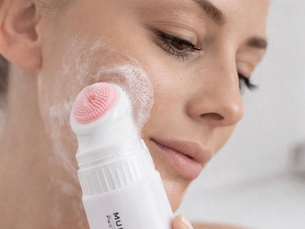 Aplicación del gel limpiador facial con cepillo de silicona sobre la piel húmeda para limpieza profunda diaria.