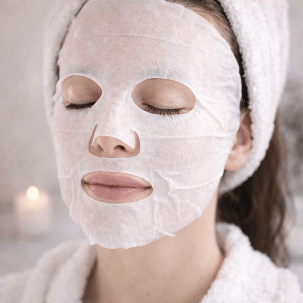 Mascarilla facial calmante en tissu ESSENS aplicada sobre el rostro, ideal para hidratar y calmar la piel tras el estrés o la deshidratación.
